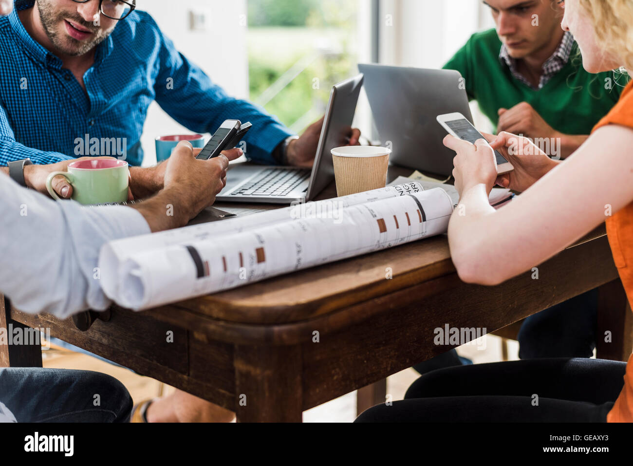 Collègues à table avec des téléphones portables, ordinateur portable et le plan Banque D'Images