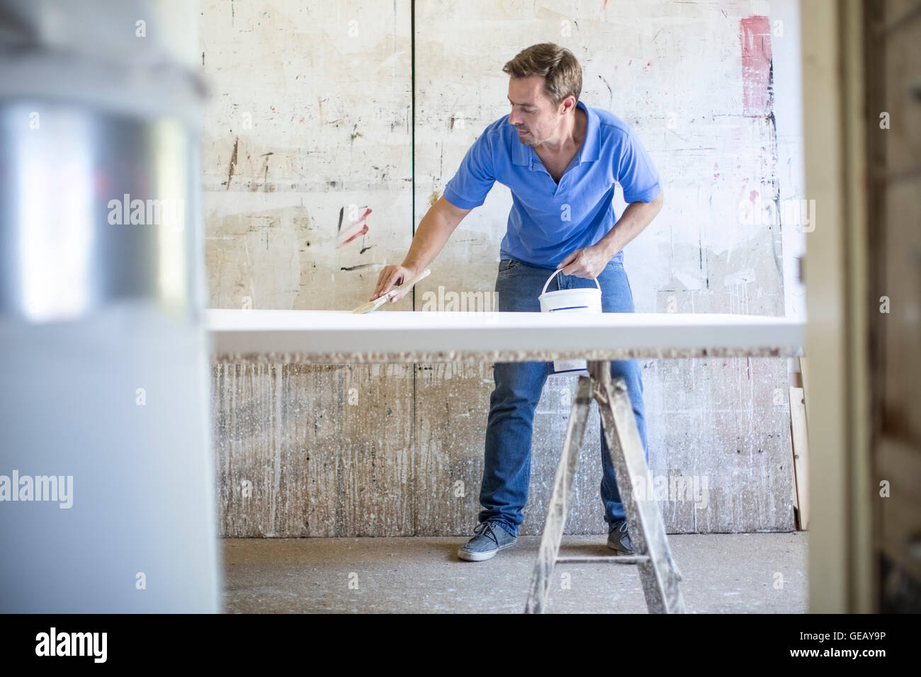 L'homme l'application de couche de peinture sur le cadre du tapis Banque D'Images