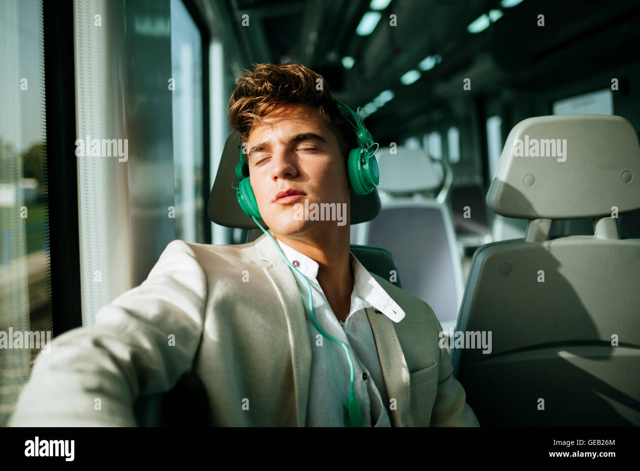 Jeune homme avec un casque de dormir sur un train Banque D'Images