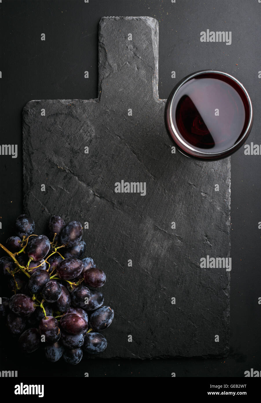 Verre de vin rouge et les raisins sur noir ardoise sur fond sombre Banque D'Images