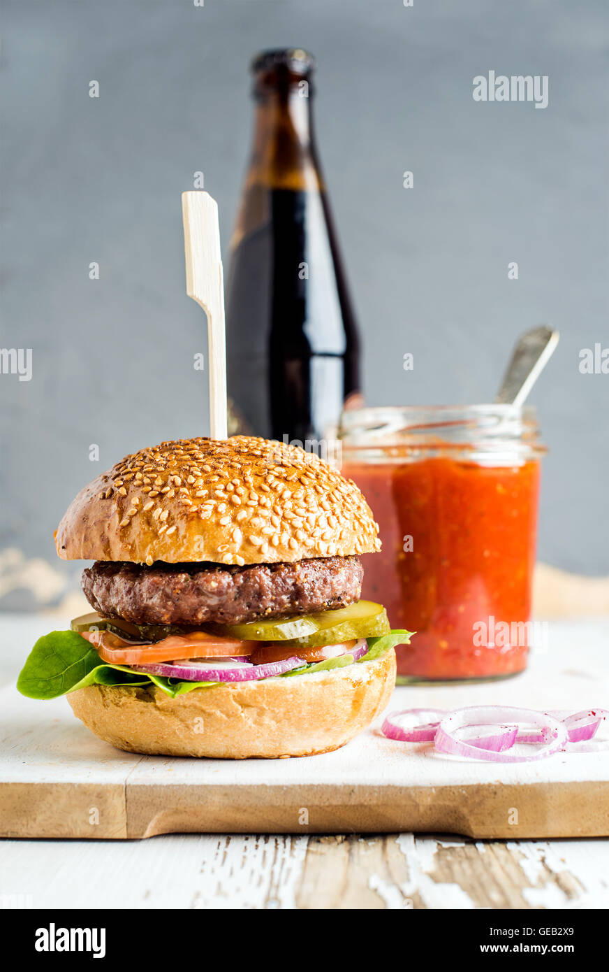 Burger maison en bois servant à bord avec sauce tomate piquante et  bouteille de bière brune, fond blanc Photo Stock - Alamy