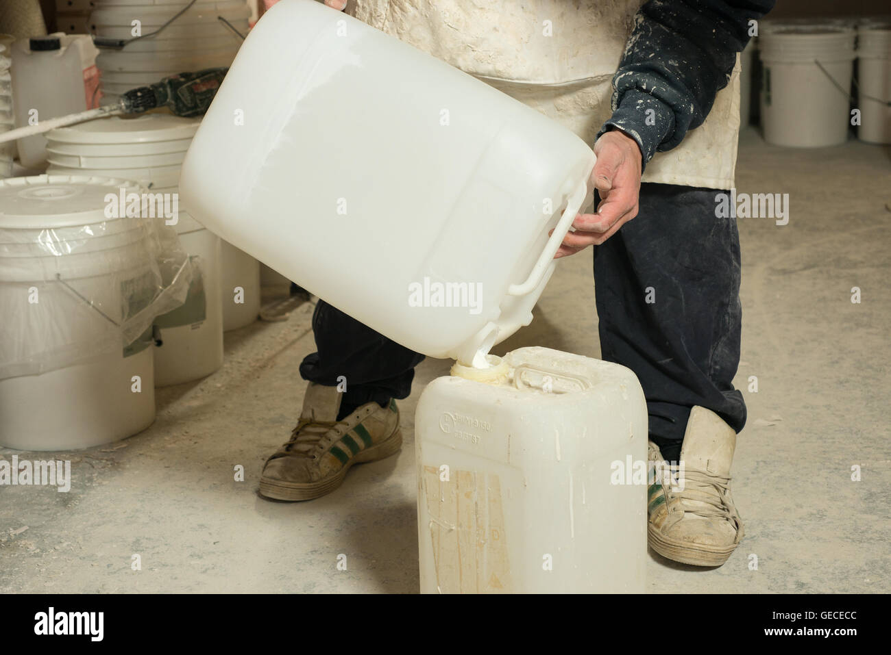 Un homme versant plâtre liquide résine dans un grand récipient en plastique blanc Banque D'Images