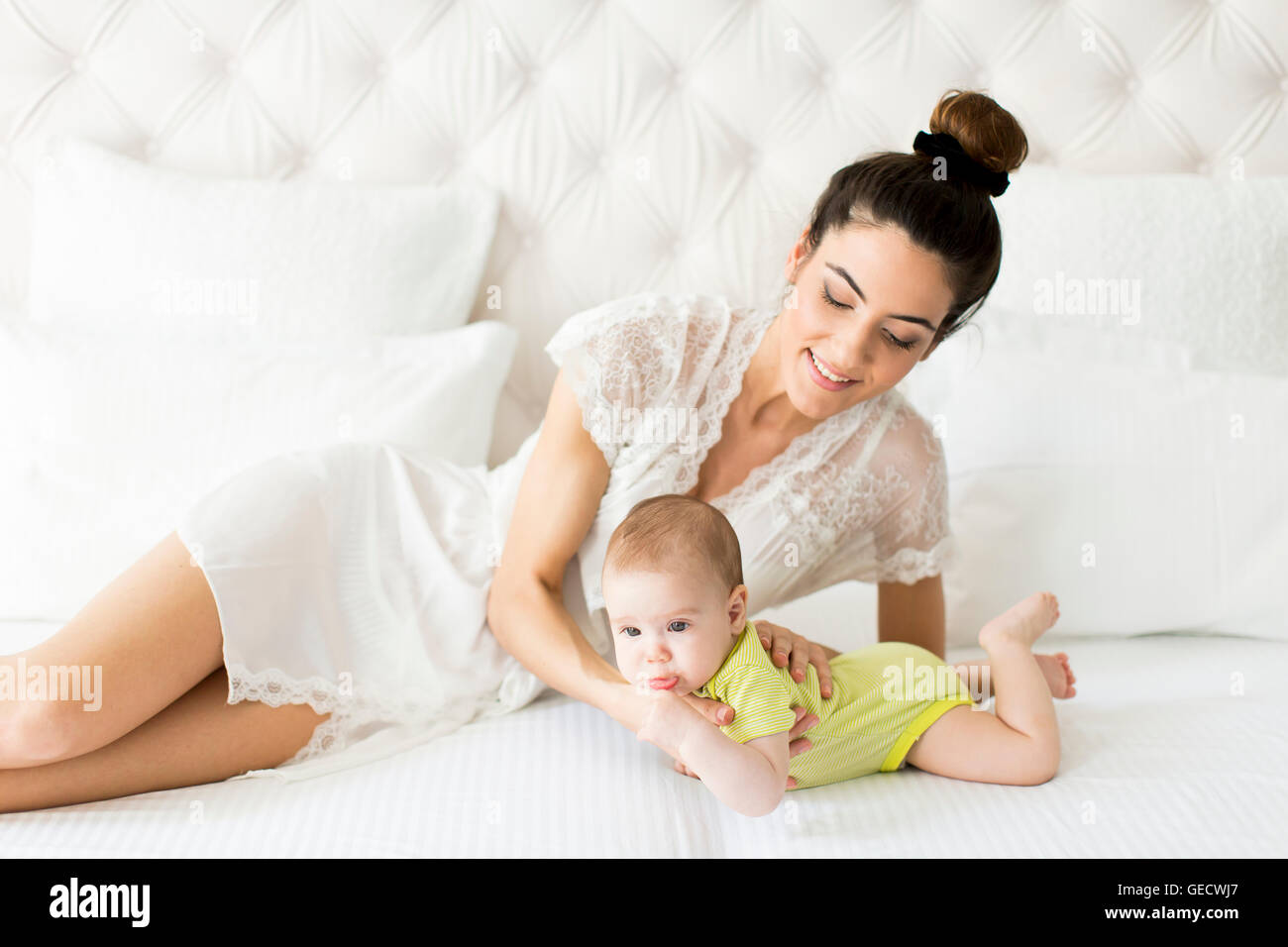 Jeune maman avec un bébé sur le lit Banque D'Images