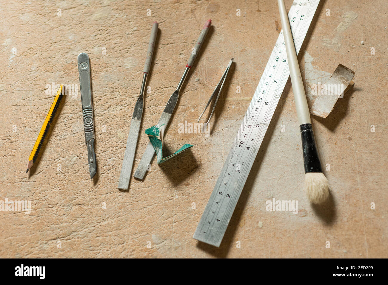 Un crayon, couteau de précision, une paire de fichiers, une paire de pinces, une règle métallique, pinceau, et utilisé des bandes de papier de verre sur un travail Banque D'Images