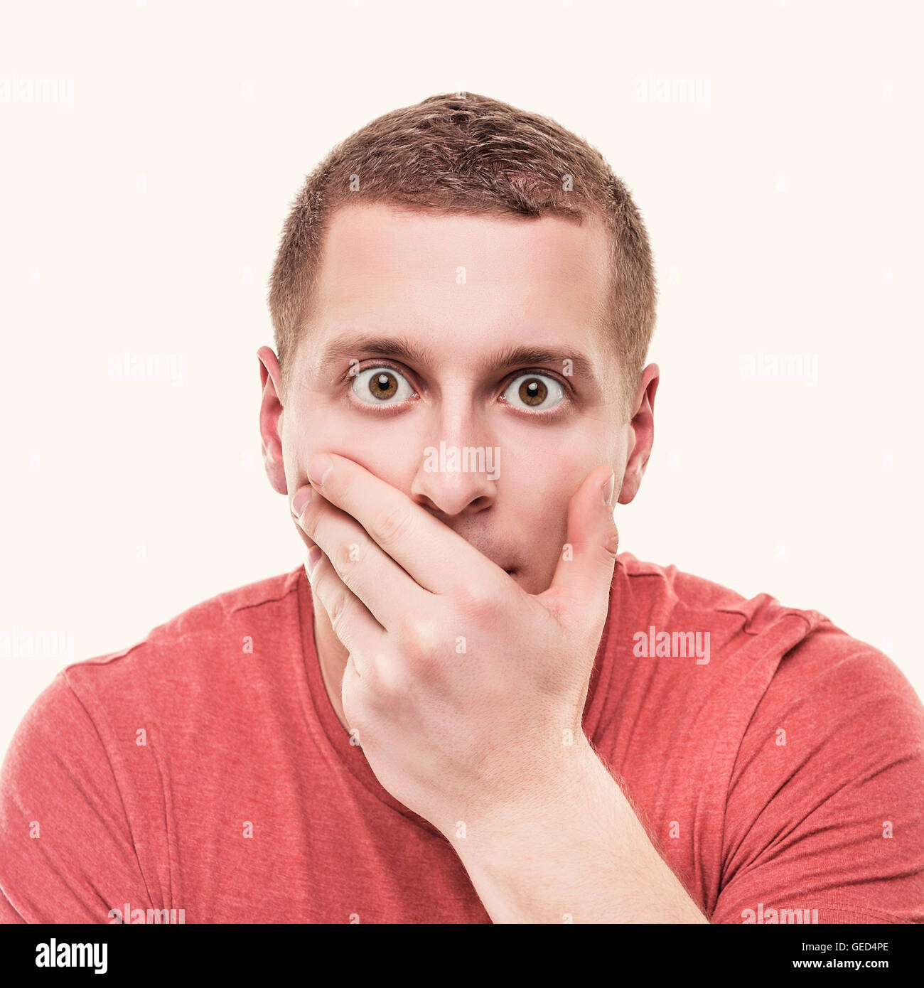 Homme choqué couvre sa bouche sur un fond blanc. Tonique photo. Banque D'Images