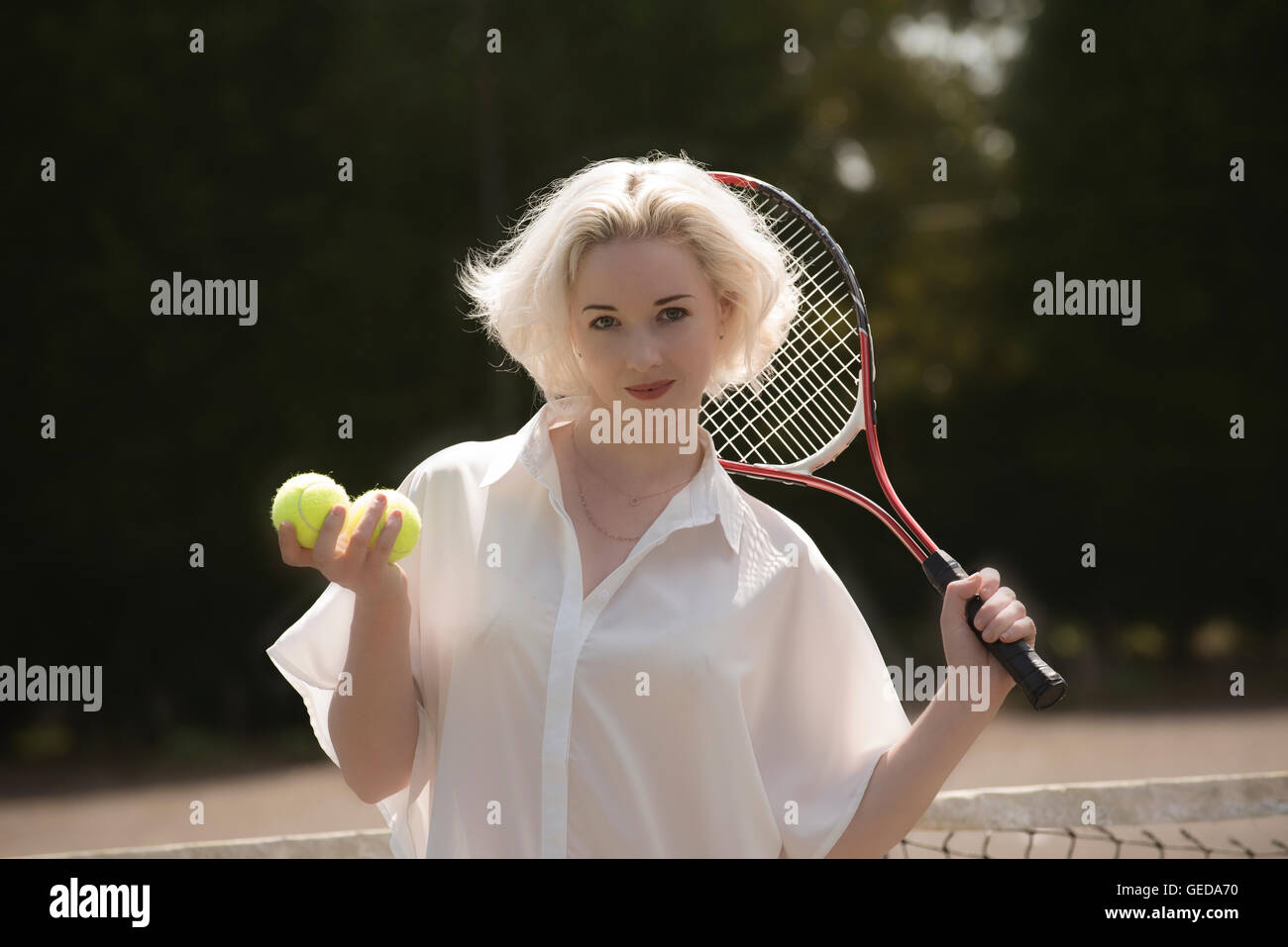 PORTRAIT D'un jeune joueur de tennis. Un jeune joueur de tennis féminin avec les cheveux clairs holding une raquette et balles de tennis Banque D'Images