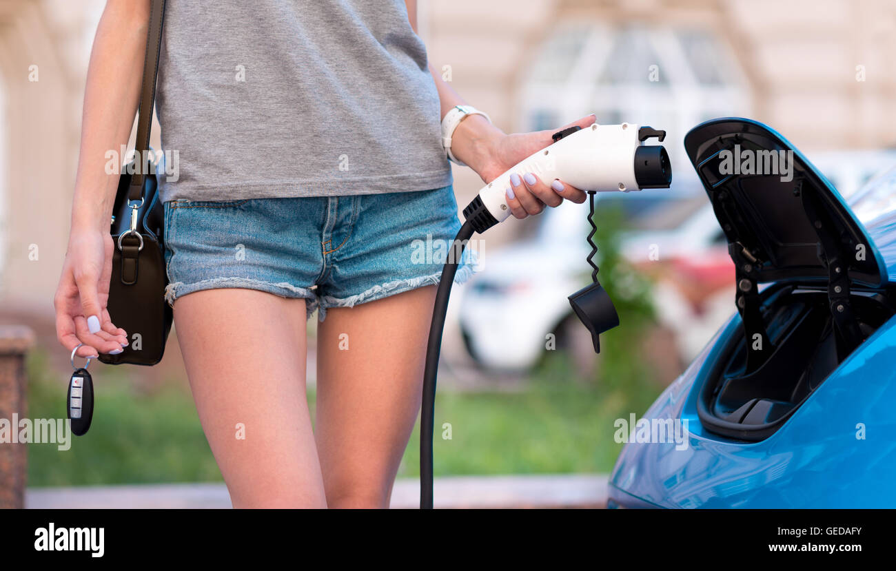 Femme tenant le câble de charge de voiture électrique Banque D'Images