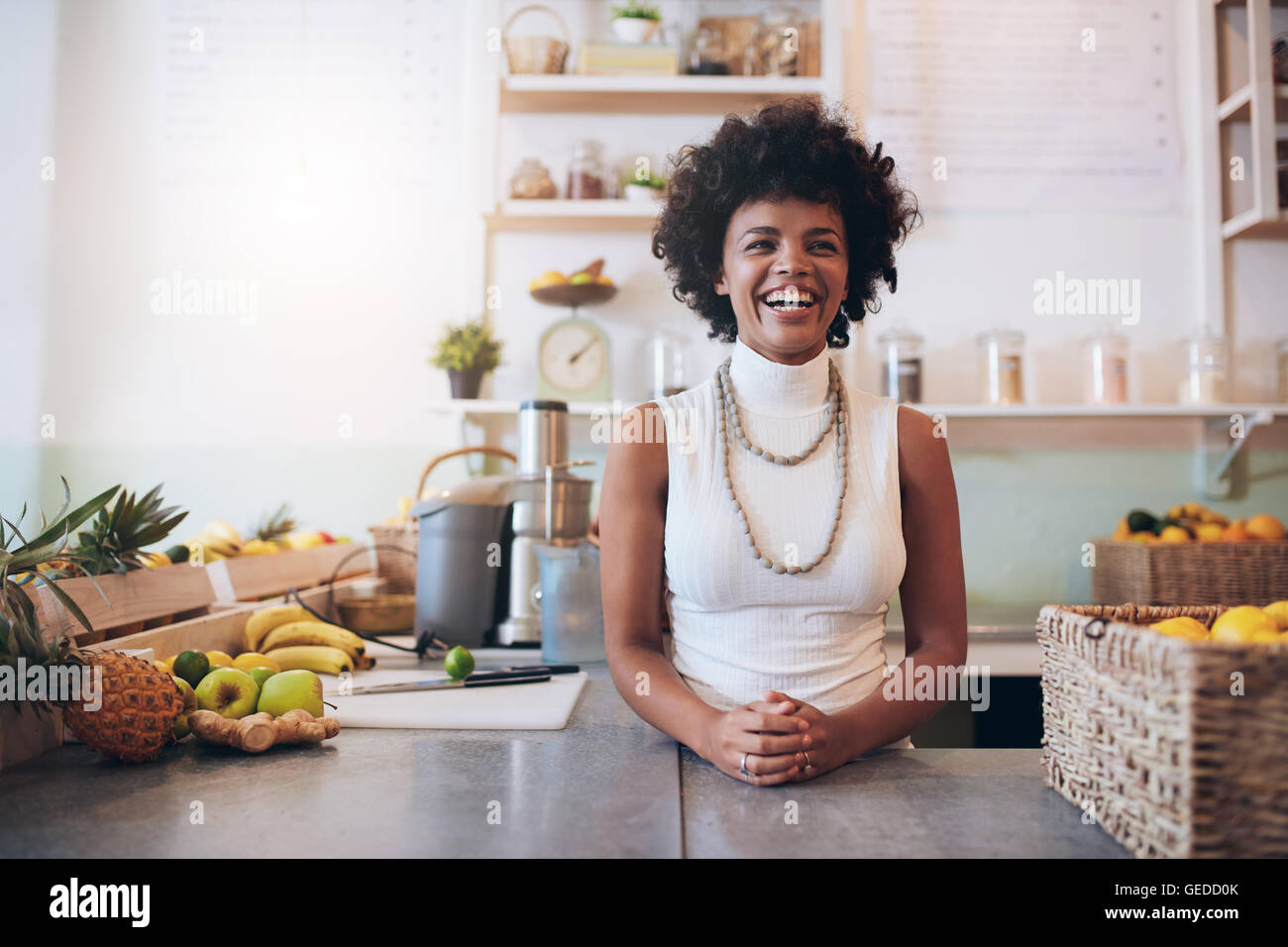 Portrait de jeune femme africaine debout derrière un bar de jus de compteur et souriant. Heureux propriétaire d'un bar à jus. Banque D'Images