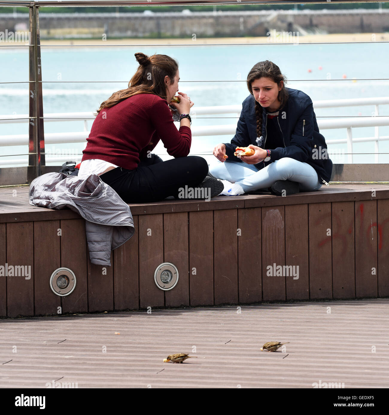 Deux jeunes femmes les filles de manger des sandwichs au déjeuner et se nourrir les moineaux à San Sebastián‡n Donostia Espagne Banque D'Images