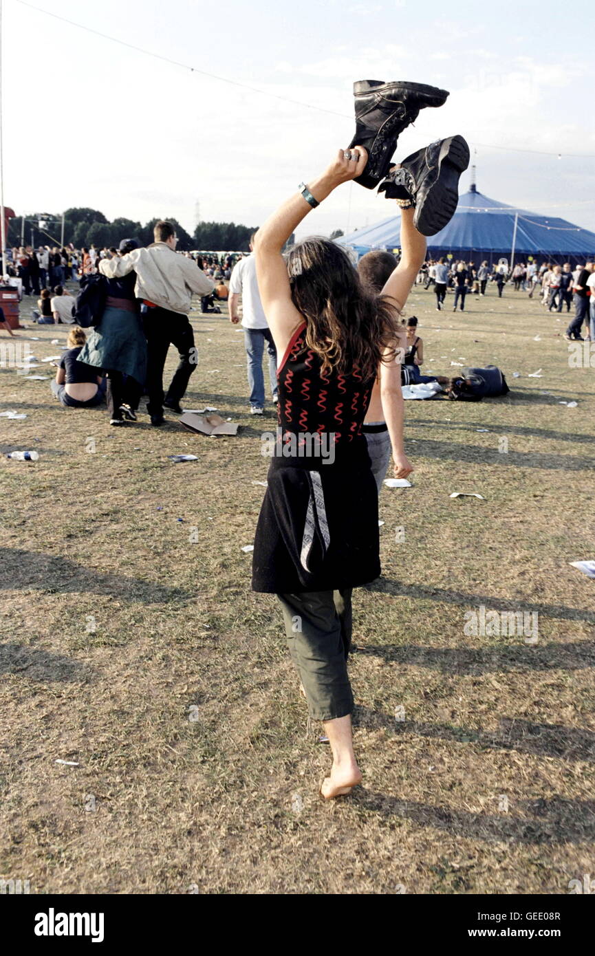 Une femme tenant ses grandes bottes danse autour de Hackney Wick, Festival. Londres 1990 Banque D'Images Une femme tenant ses grandes bottes danse autour de Hackney Wick, Festival. Londres 1990 Banque D'Images