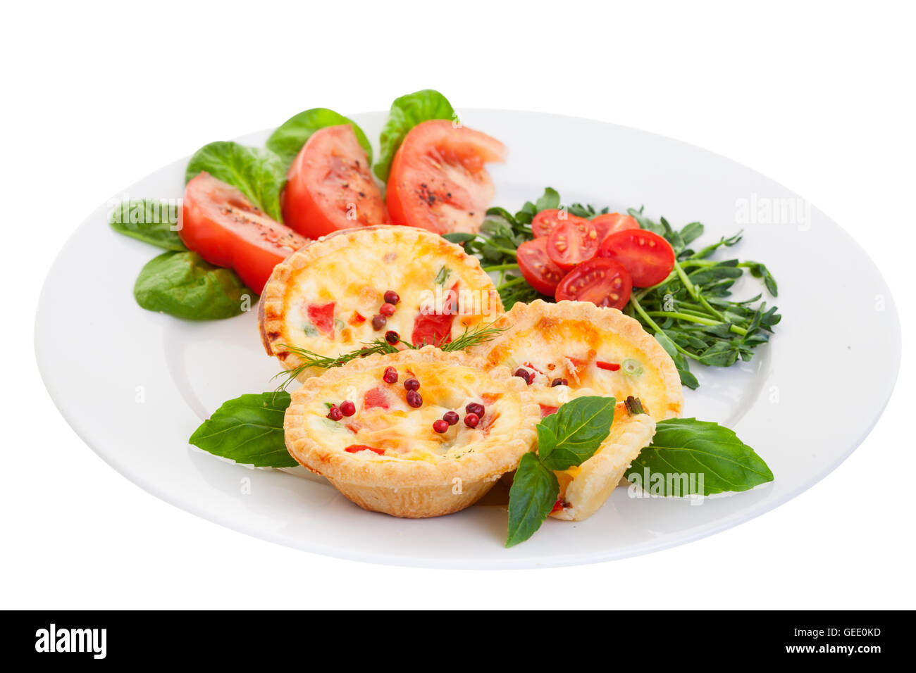 Assiette de Mini quiche sur fond blanc remplie de légumes avec salade.Focus sur la face avant des tartes. Banque D'Images