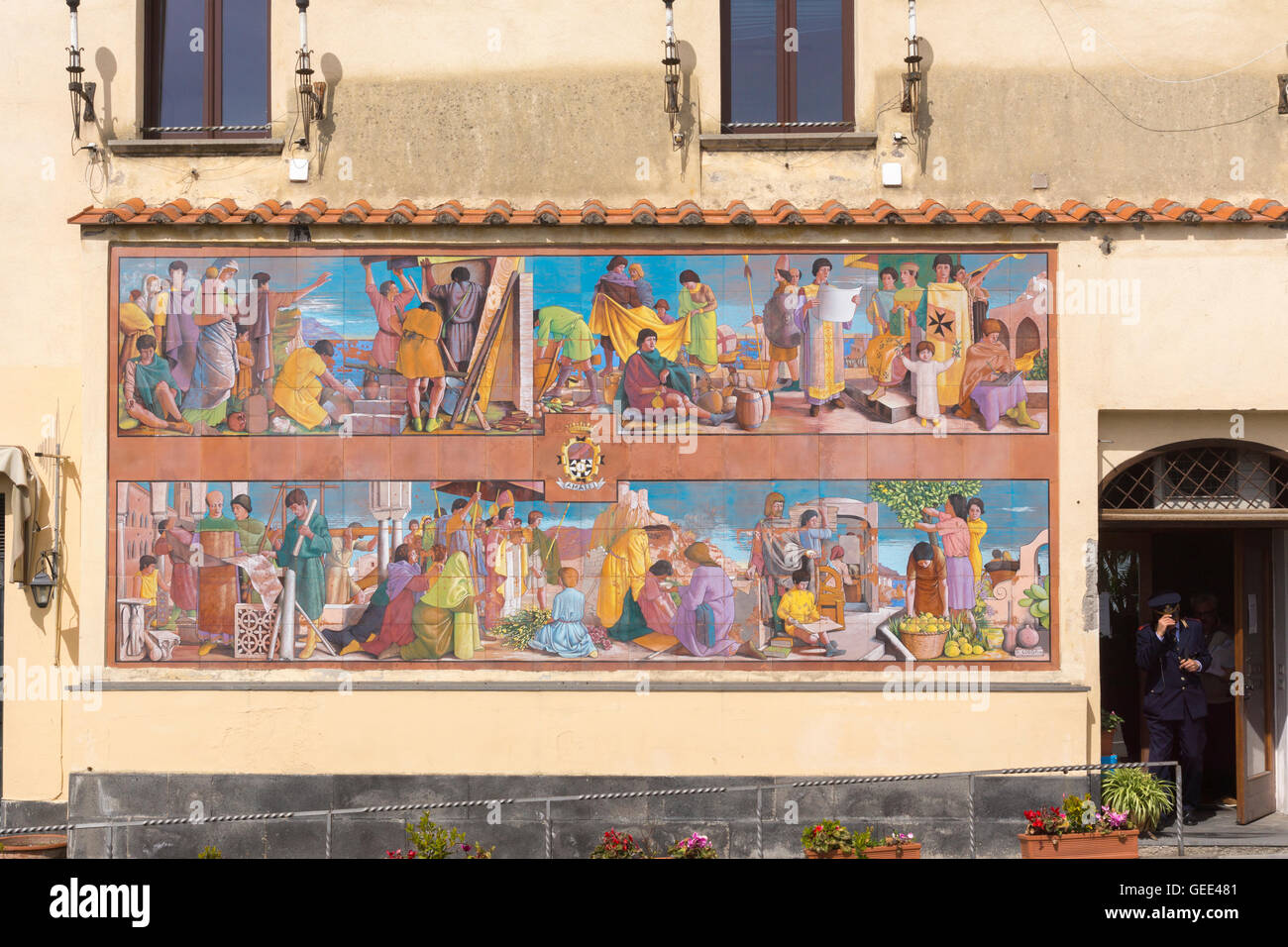 Un agent de police pas hors d'un bâtiment à côté d'une grande scène religieuse peint sur les carreaux muraux dans Amalfi Banque D'Images