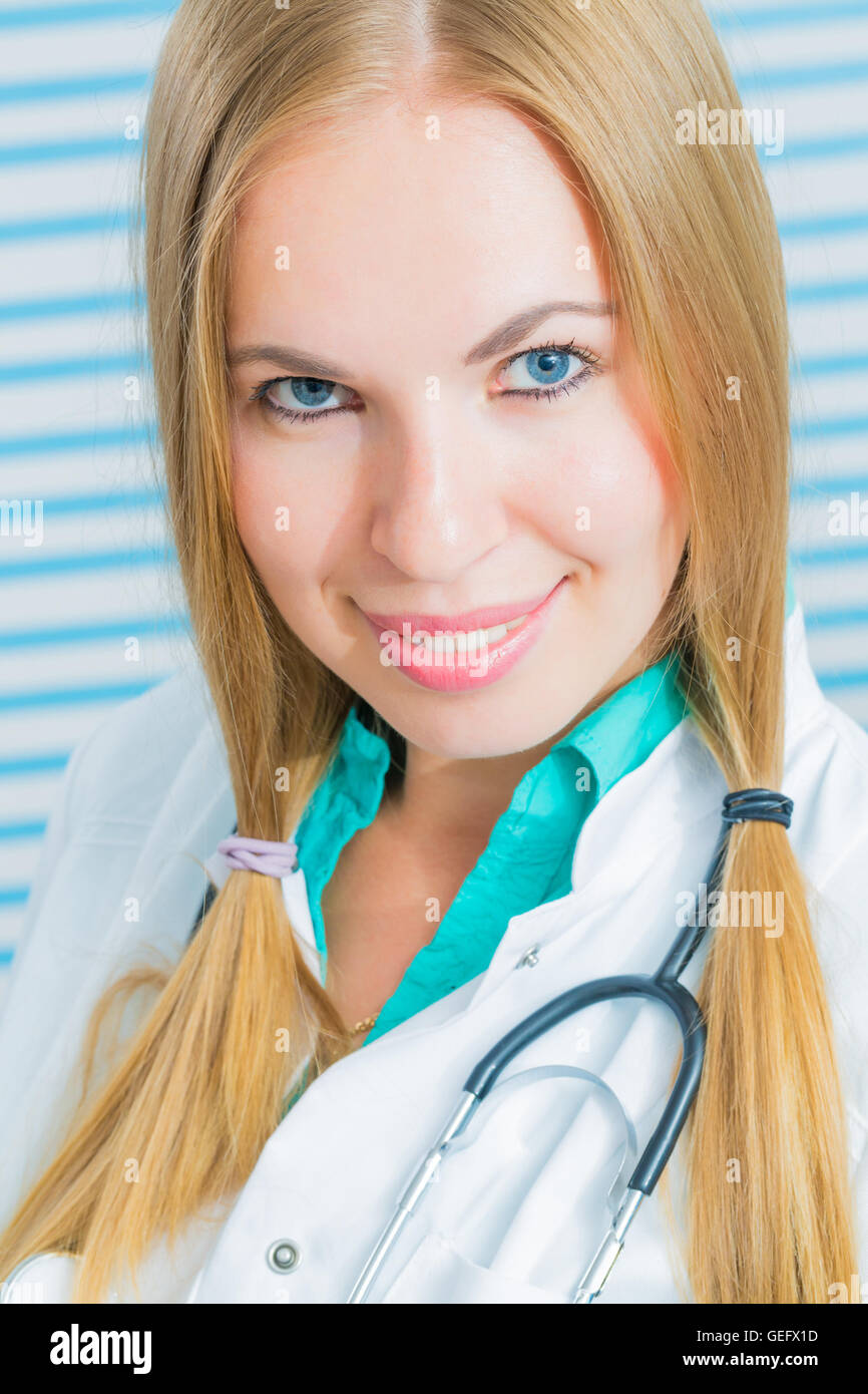 Infirmière avec de longs cheveux blonds et un stéthoscope dans un uniforme smiling at the camera Banque D'Images