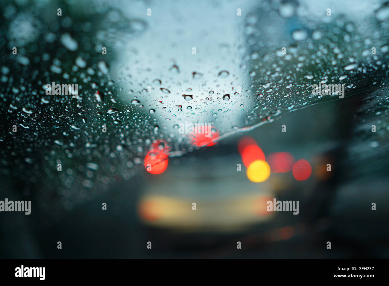 Gouttes de pluie sur le pare-brise avec l'arrière-plan de circulation floue Banque D'Images