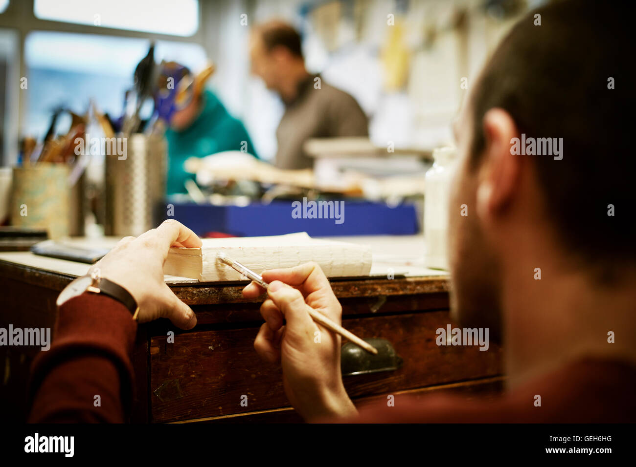 Un homme travaillant sur les pages d'un livre avec un outil à main, d'appliquer la colle. Banque D'Images