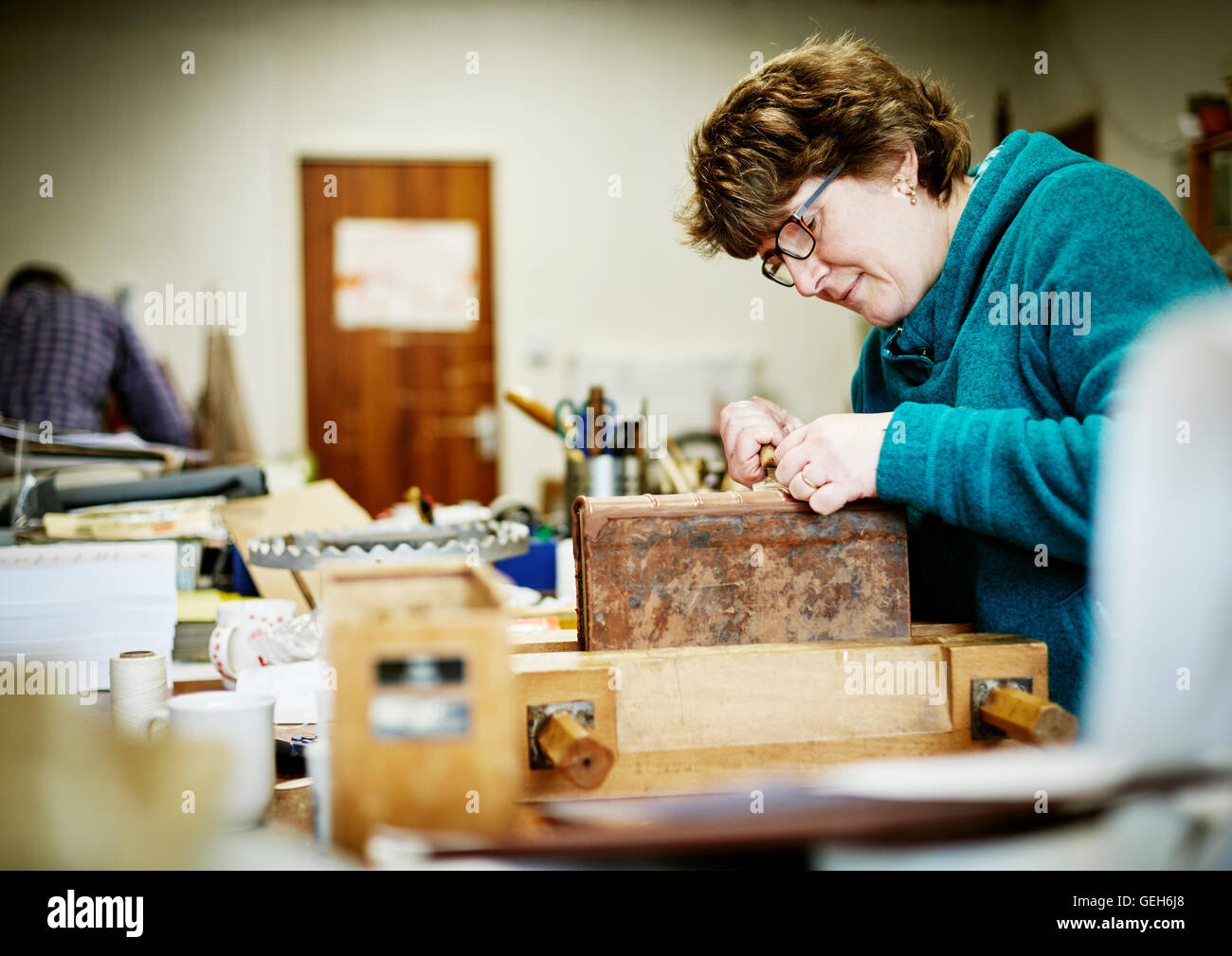 Une femme travaillant à un banc sur la reliure d'un livre dans le besoin de restauration. Banque D'Images