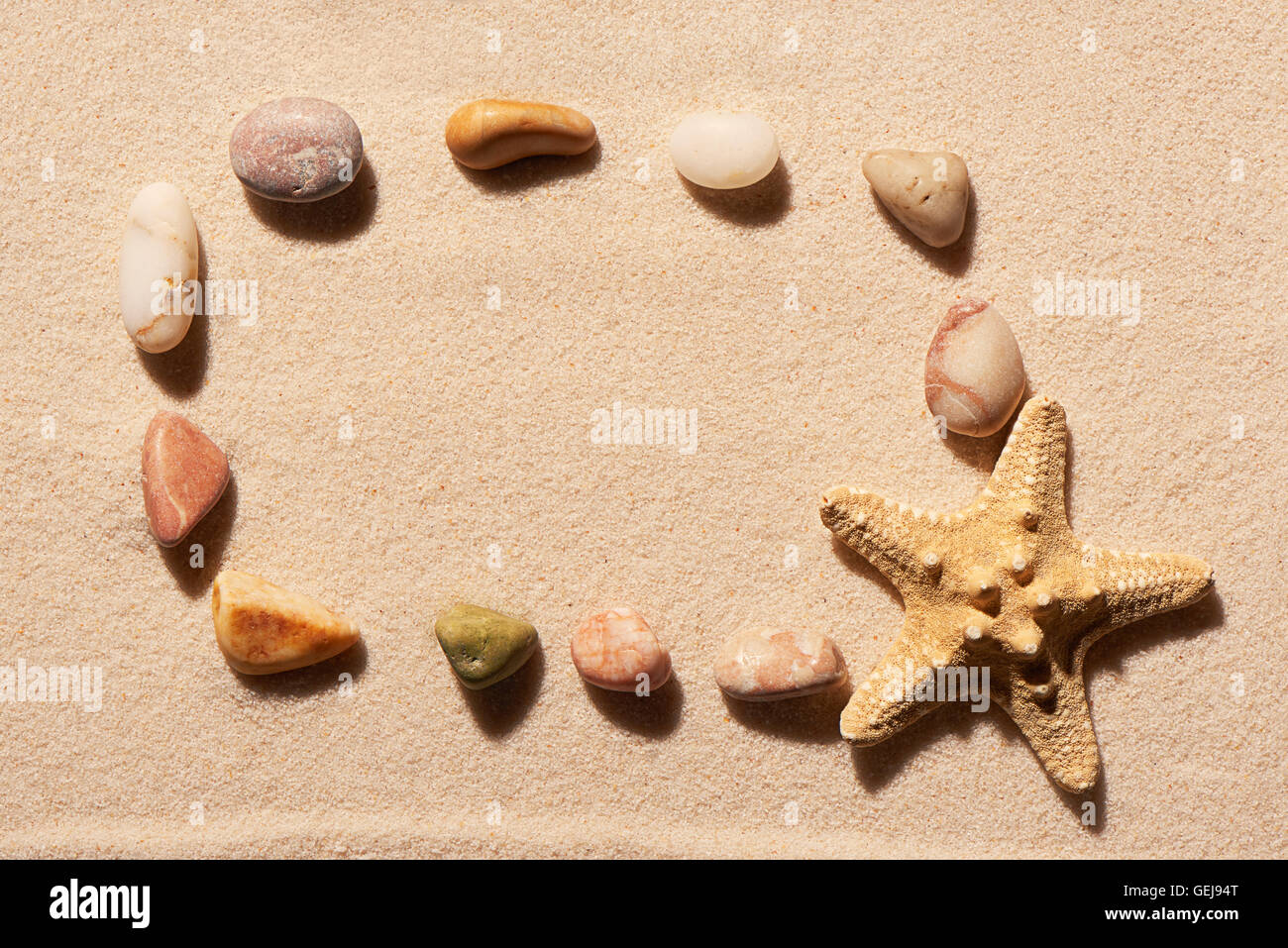 Cadre rectangulaire de pierres et d'étoiles de mer sur le sable. Fond de plage d'été. Vue de dessus Banque D'Images