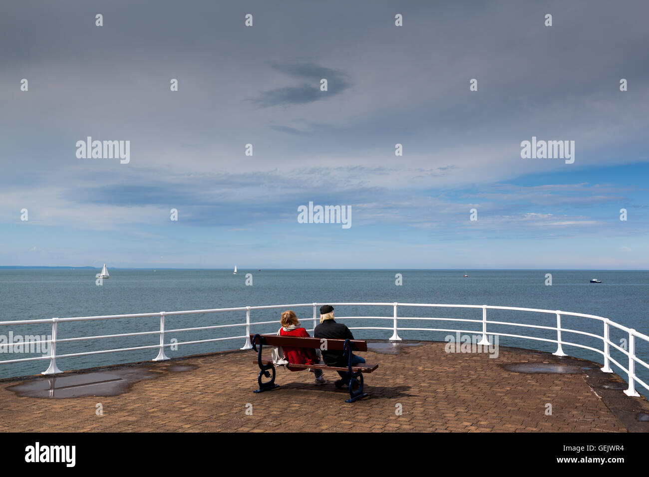 Un couple de personnes âgées assis sur un banc face à la mer à Aberystwyth Banque D'Images