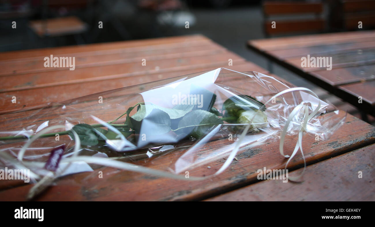 Ansbach, Allemagne. 26 juillet, 2016. Une rose blanche dans du cellophane se trouve sur une table sur le site de l'attaque dans la cour de 'Eugen's Weinstube' à Ansbach, Allemagne, 26 juillet 2016. 15 personnes ont été blessées dans une attaque motivée-islamistes présumés le 24 juillet 2016. L'auteur présumé, un homme de 27 ans pour les réfugiés en provenance de Syrie, a été tué dans l'explosion. Photo : DANIEL KARMANN/dpa/Alamy Live News Banque D'Images