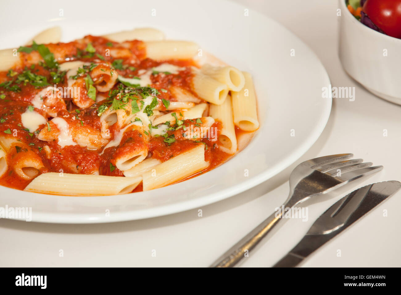 Close-up de pâtes penne arabiata fraîchement garnie de persil vert Banque D'Images