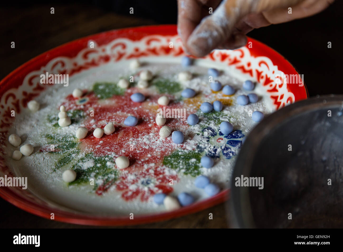 Tourné vers le bas avec les doigts la main pourpre moulage pâte bleue et de la placer sur un plateau coloré avec des bonbons blanc Banque D'Images