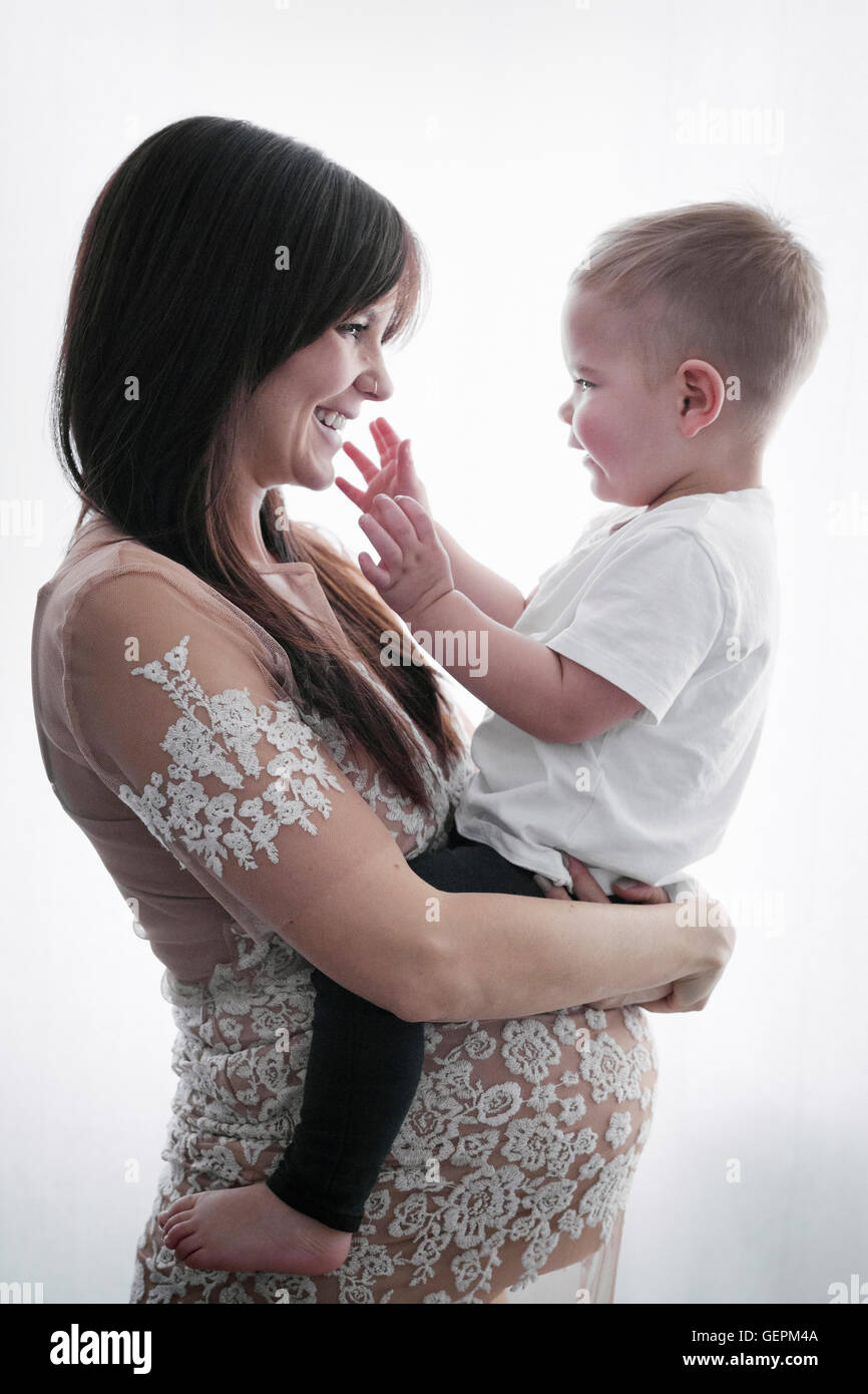 Une femme enceinte tenant son jeune fils dans ses bras. Banque D'Images