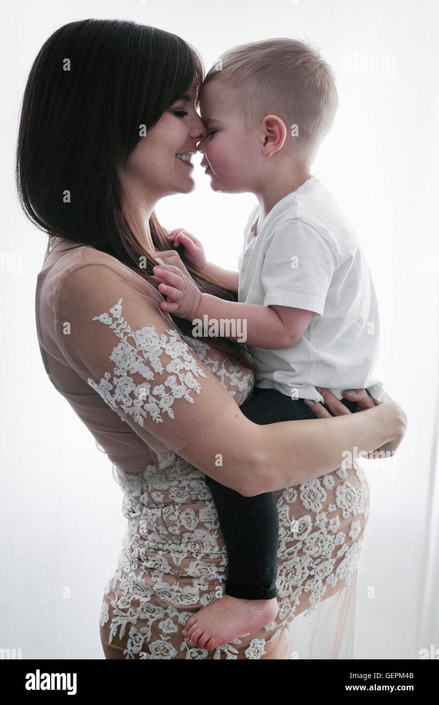 Une femme enceinte tenant son jeune fils dans ses bras. Banque D'Images
