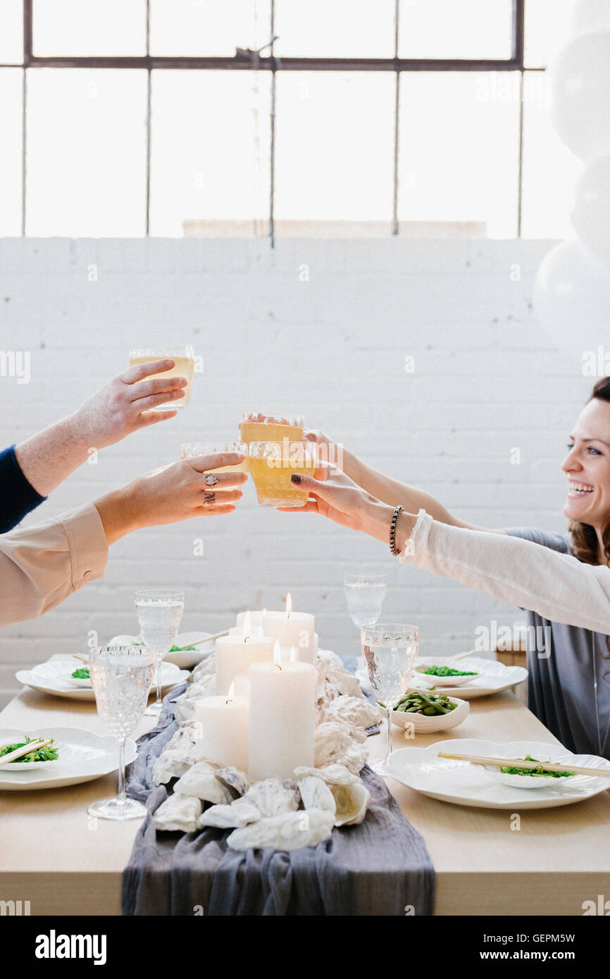 Quatre personnes d'augmenter leurs verres dans un toast lors d'un repas. Banque D'Images