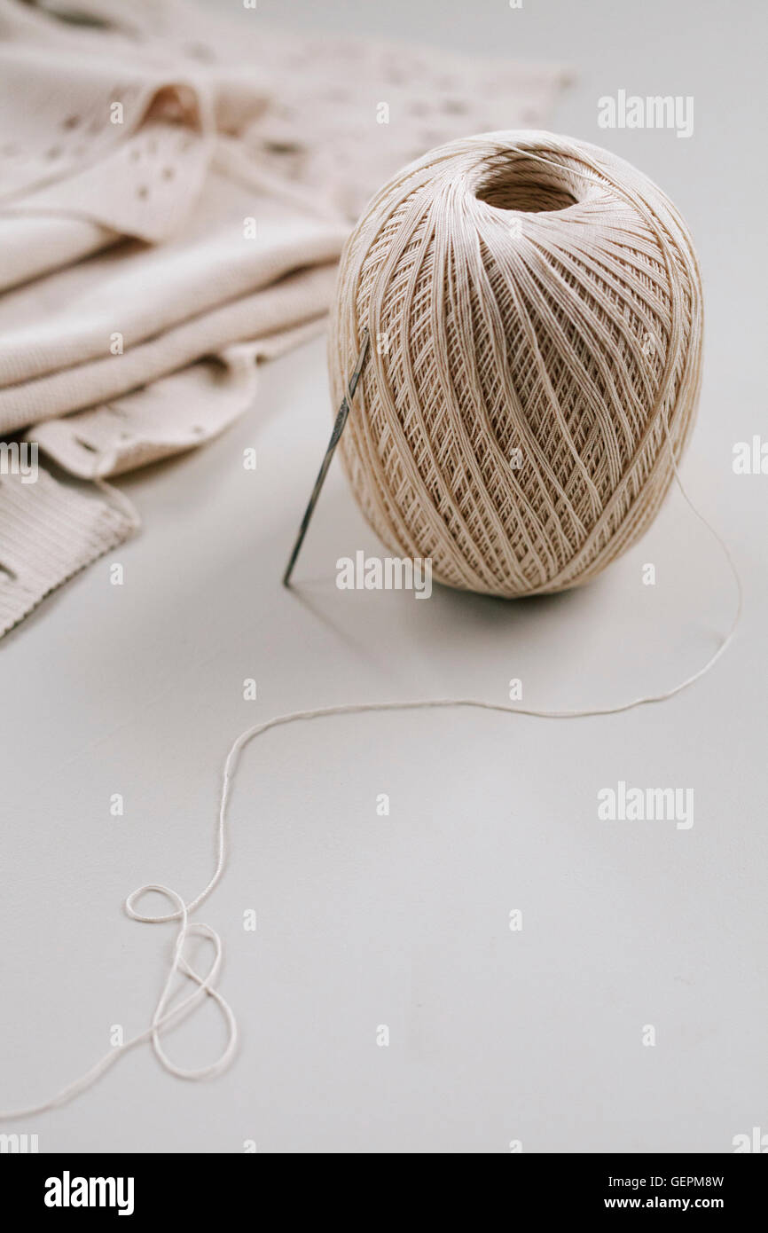 Une pelote de ficelle ou de fil et une aiguille ou crochet métallique avec tissu plié. Banque D'Images
