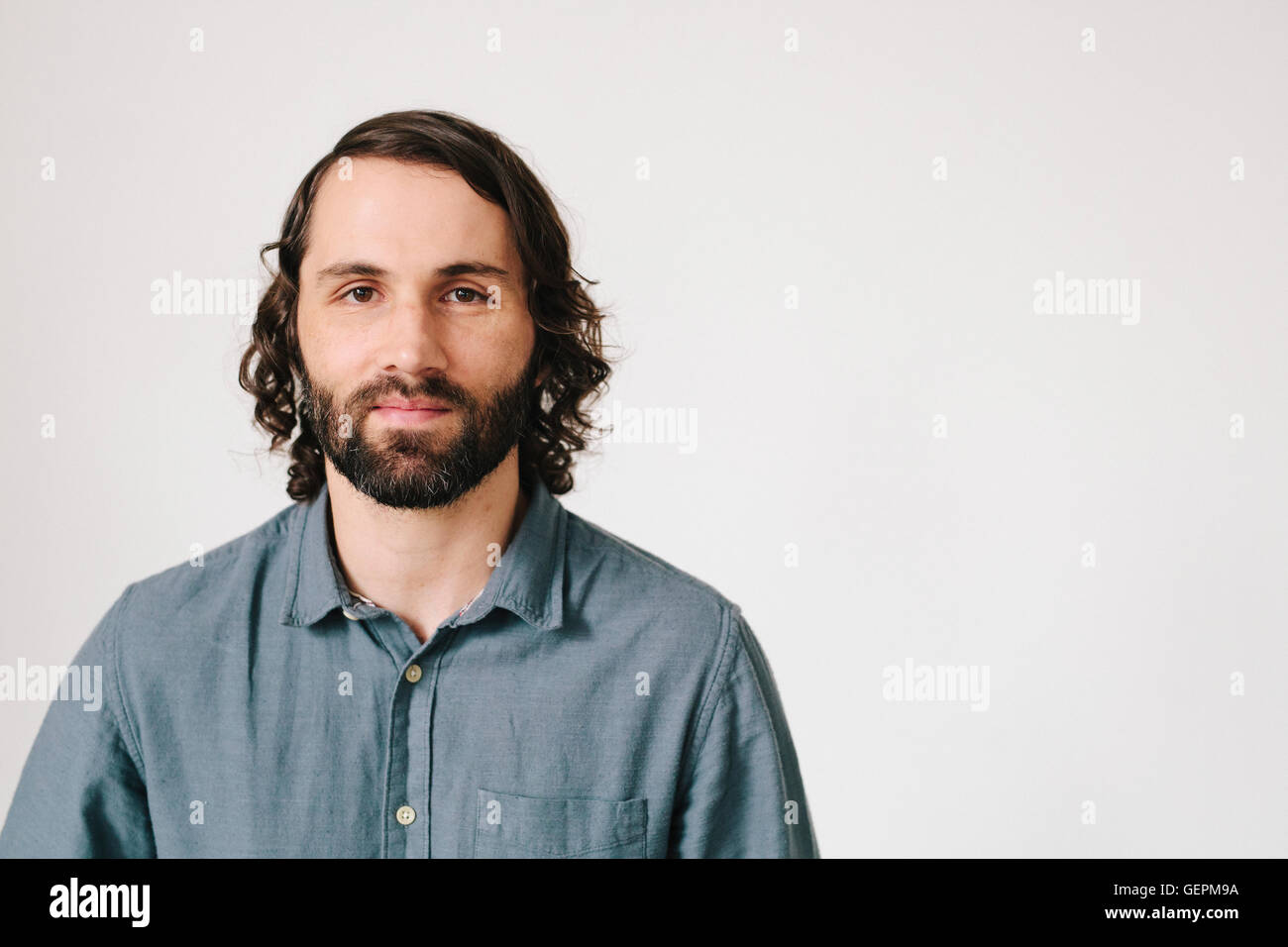 Un jeune homme barbu dans une chemise bleue, regardant la caméra. Banque D'Images
