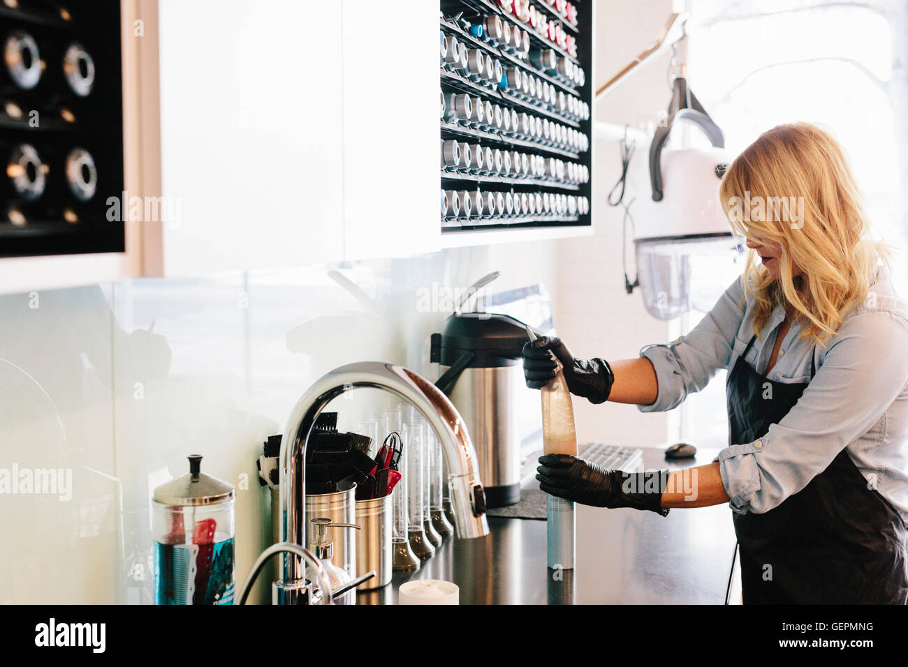 Une femme portant des gants de travail, le nettoyage de l'équipement à un salon de coiffure. Banque D'Images