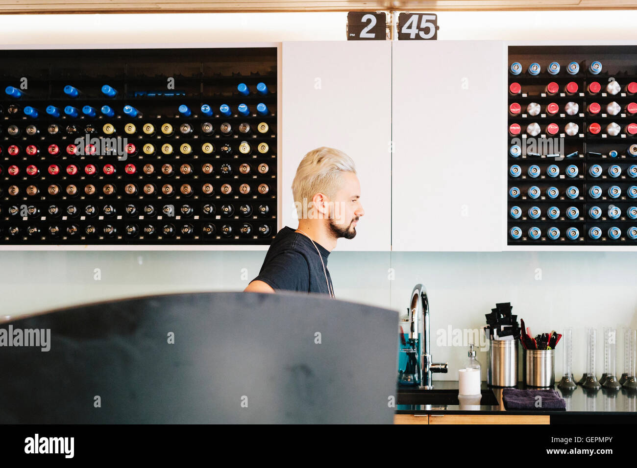 Un homme de profil debout par un évier dans un salon de coiffure. Banque D'Images
