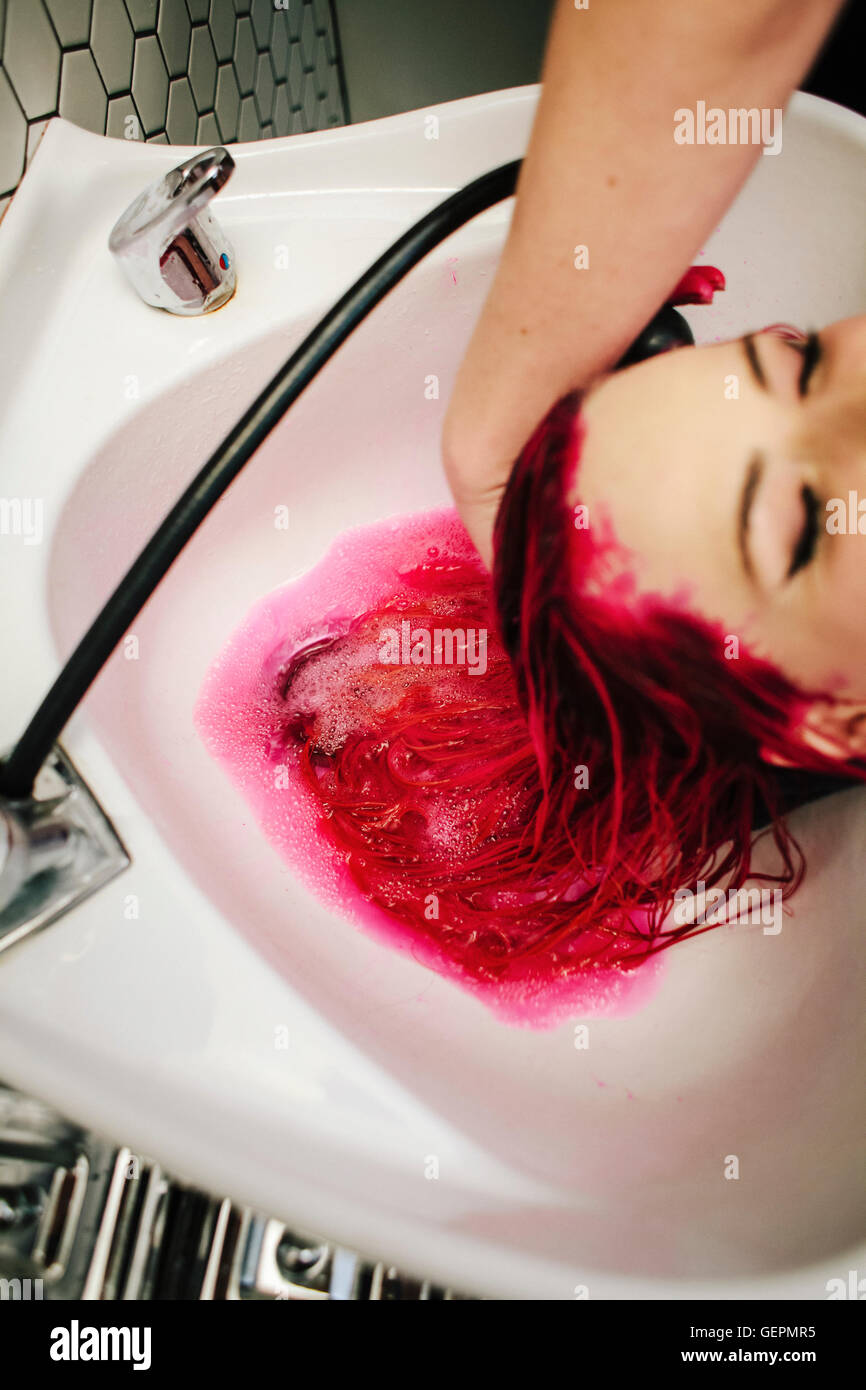 Un salon de coiffure client red hair dye rincés de ses cheveux sur un bassin. Banque D'Images