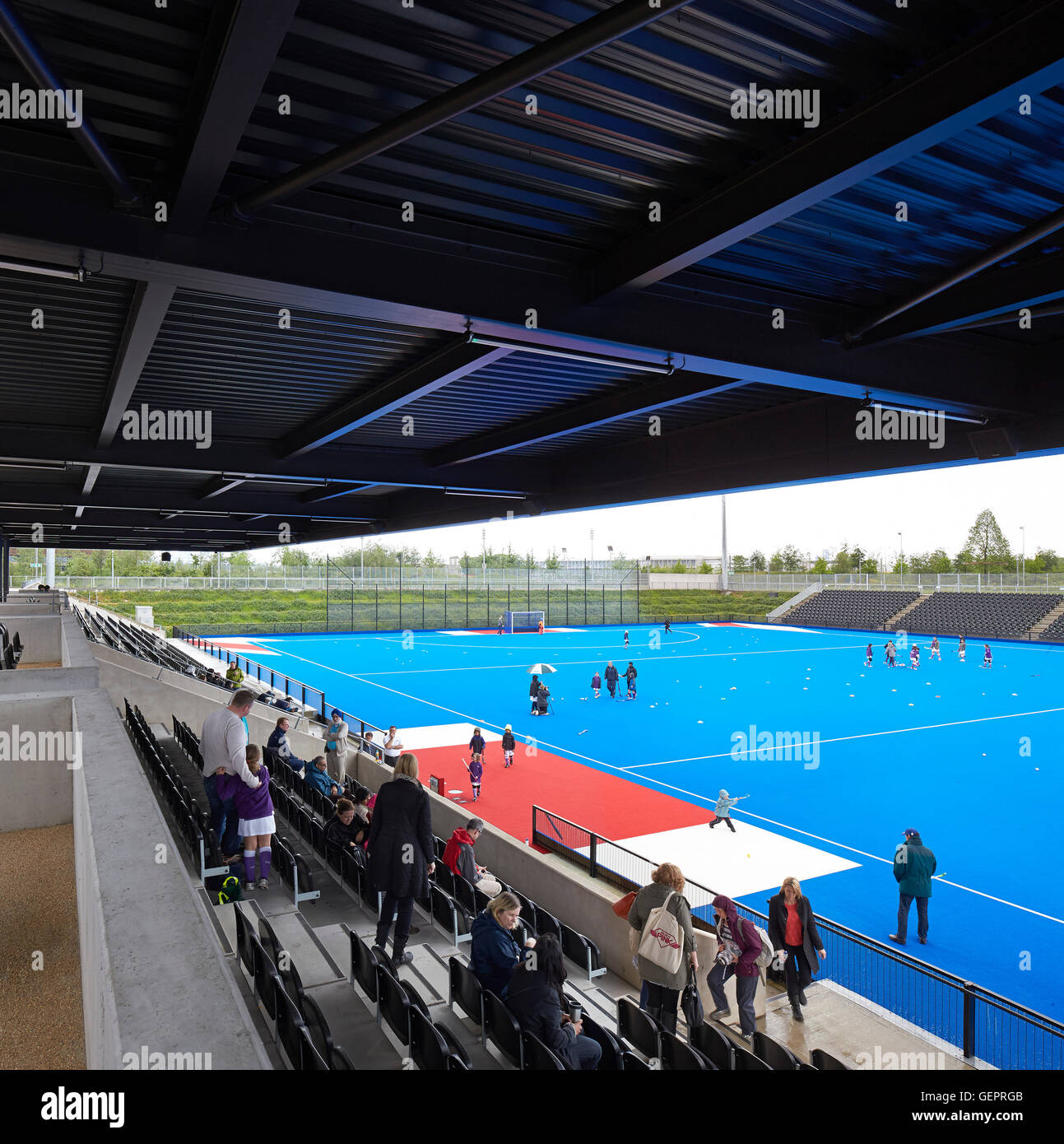 Terrain de hockey en bleu à la position du spectateur. Eton Manor - Lee Valley Hockey et Tennis Center, Londres, Royaume-Uni. Architecte : Stanton Williams, 2014. Banque D'Images