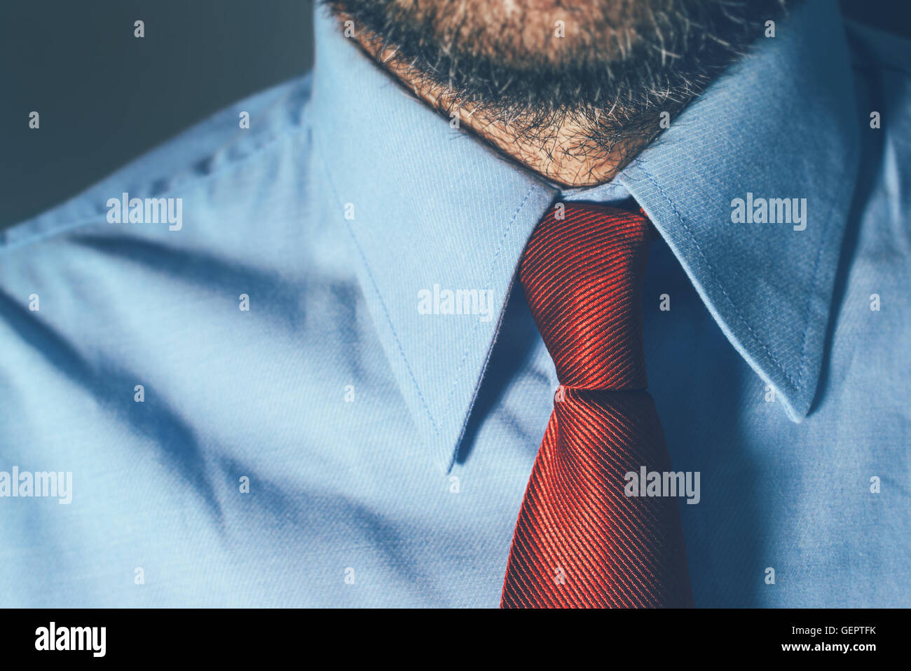Homme d'affaires en chemise bleue et cravate rouge dans office avec des ombres, adapté à la situation commerciale intense comme la rencontre Banque D'Images