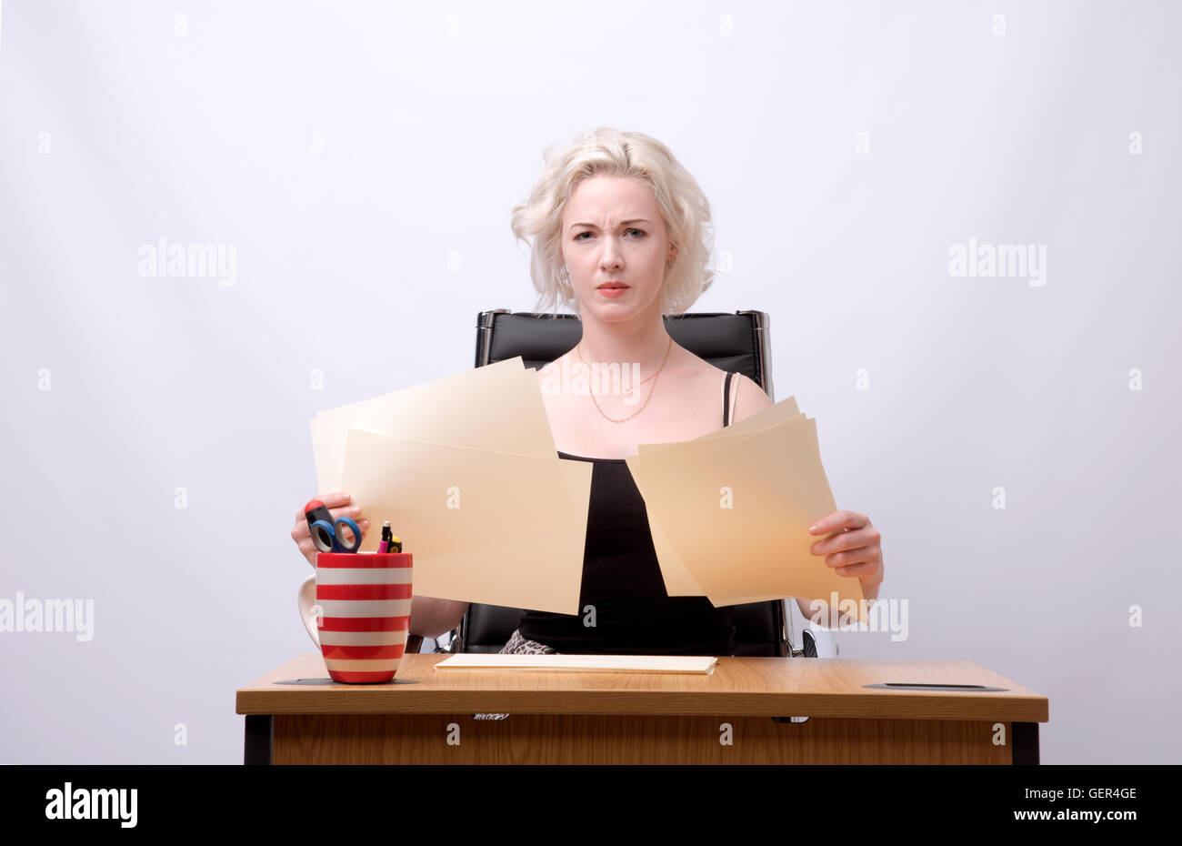 Secrétaire SITTING AT DESK HOLDING ÉCRITURE - d'un secrétaire à son bureau 24 holding papers Banque D'Images