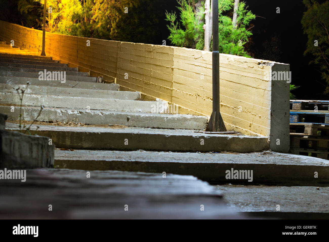 Ancien escalier en béton de la rue, éclairé par les feux de route. Calme sombre dans la nuit solitaire resort village méditerranéen. Bali, Grèce Banque D'Images