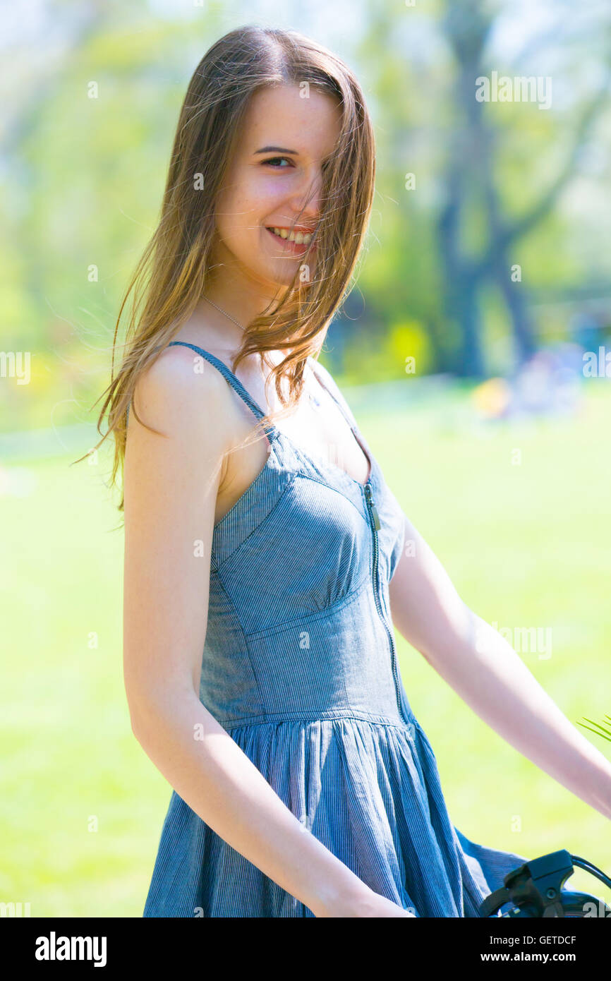 Belle jeune femme en vélo avec fleur en park Banque D'Images