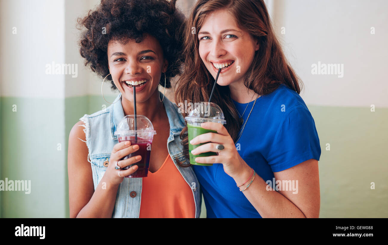 Portrait de deux jeunes amis de boire des jus de fruits. Mixed Race Women Standing together buvez du jus. Banque D'Images