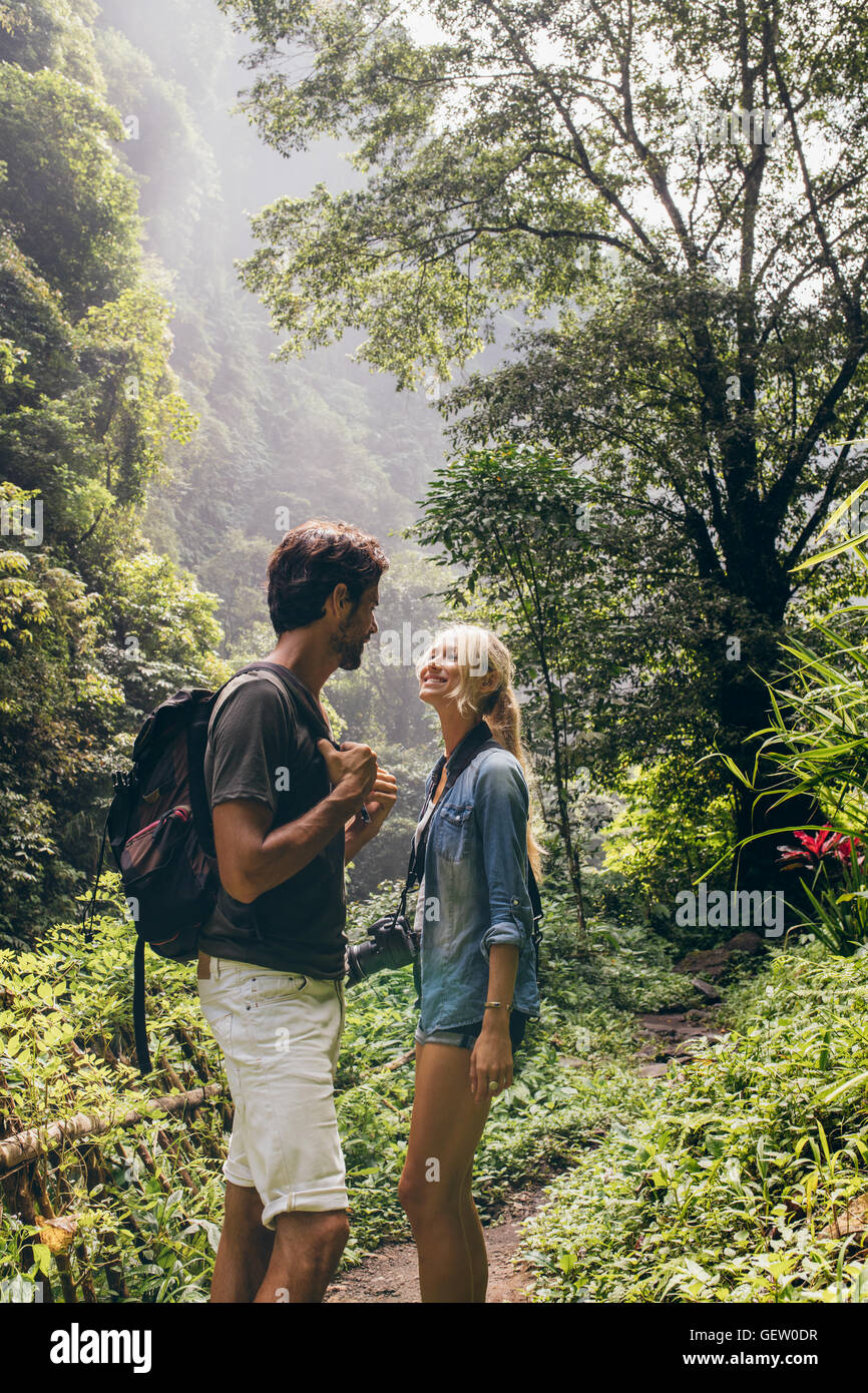 Jeune couple romantique sur sentier forestier à la recherche à l'autre et souriant. Le procès de montagne touristique. Banque D'Images
