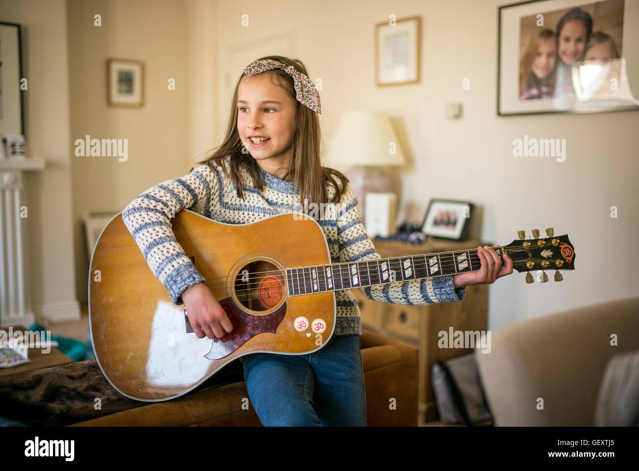 Une jeune fille jouant de la guitare à la maison. Banque D'Images