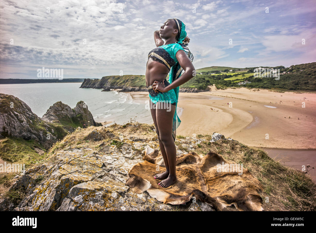 Une femme afro antillais détente sur trois collines surplombant la baie d'Clffs sur le Gower. Banque D'Images