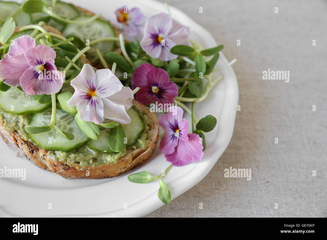 , Avocat concombre, germes de tournesol et fleurs comestibles sur des toasts au levain Banque D'Images