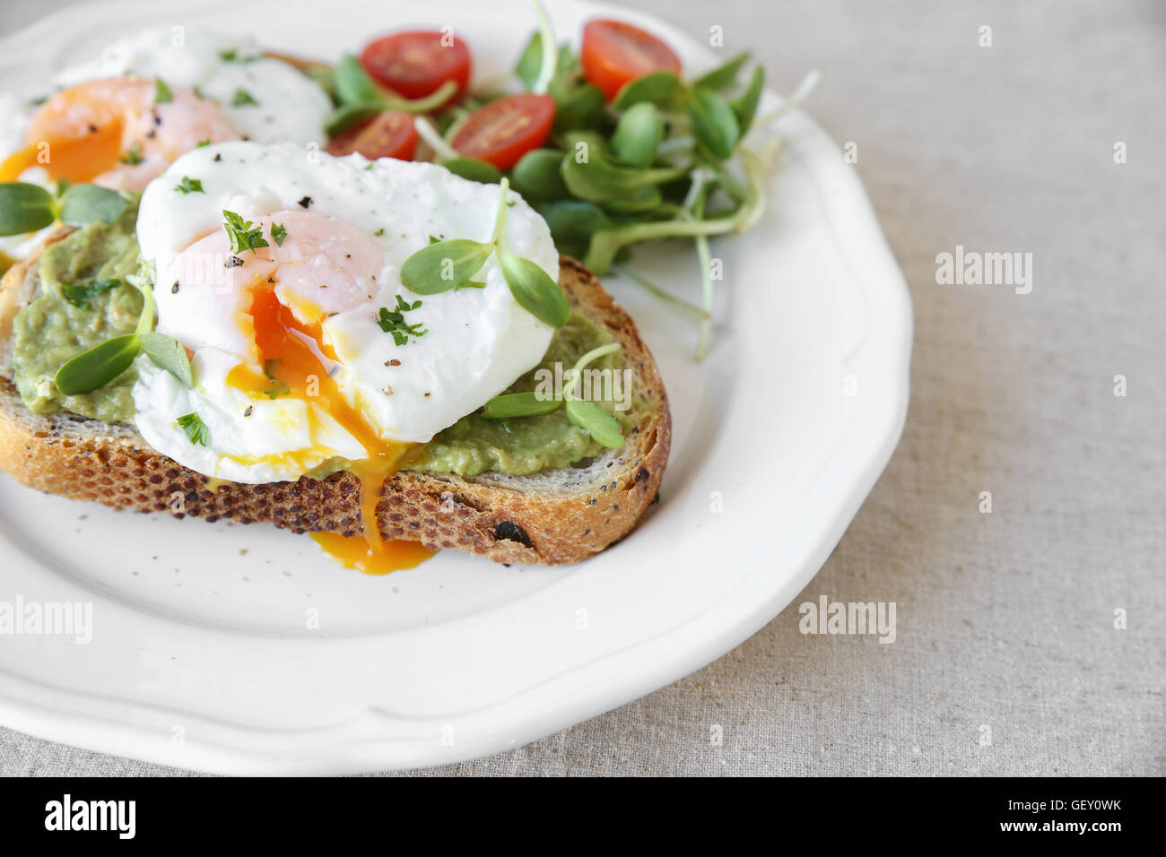 Œufs pochés à l'avocat, la tomate et le tournesol sprout sur toasts au levain Banque D'Images