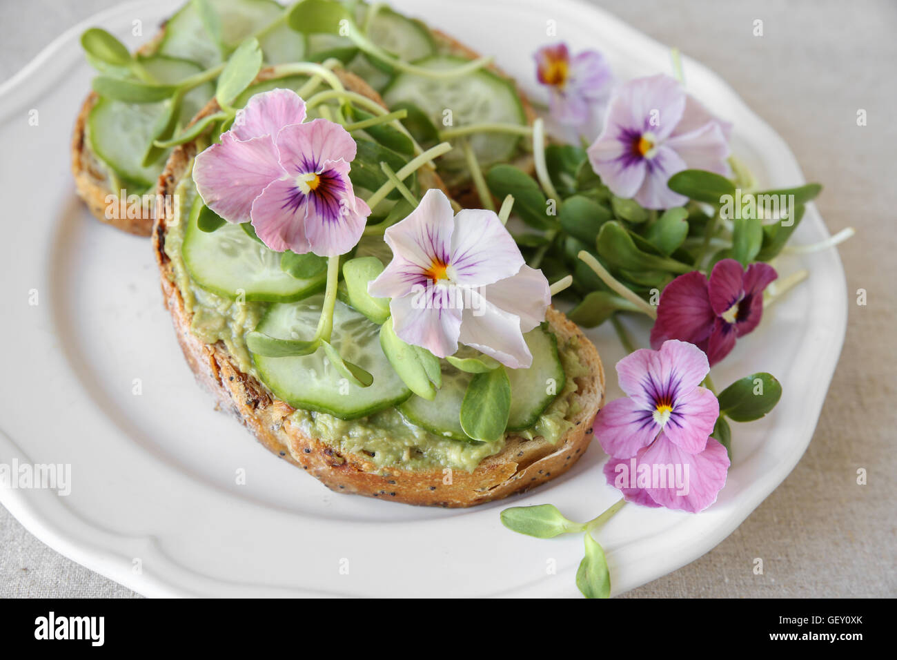 , Avocat concombre, germes de tournesol et fleurs comestibles sur des toasts au levain Banque D'Images