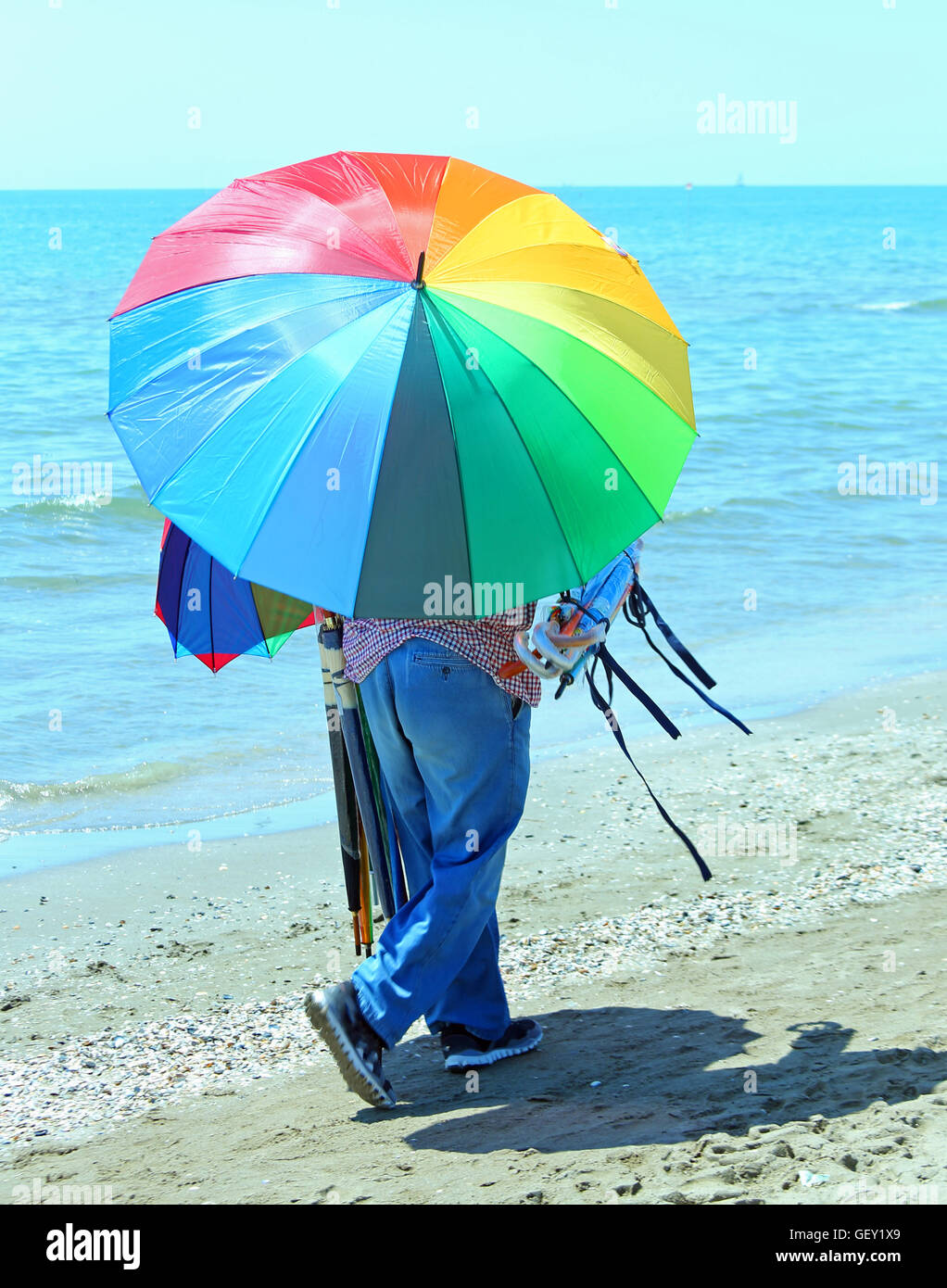 Pauvre colporteur de parasols sur la plage en été Banque D'Images