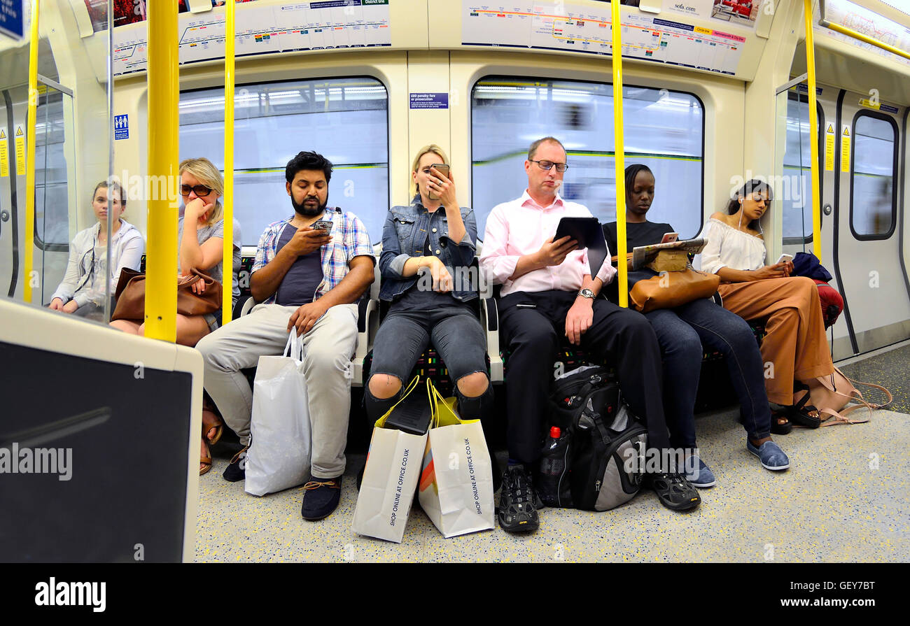 Londres, Angleterre, Royaume-Uni. Les gens sur le tube / underground, tous les téléphones mobiles / ipad Banque D'Images