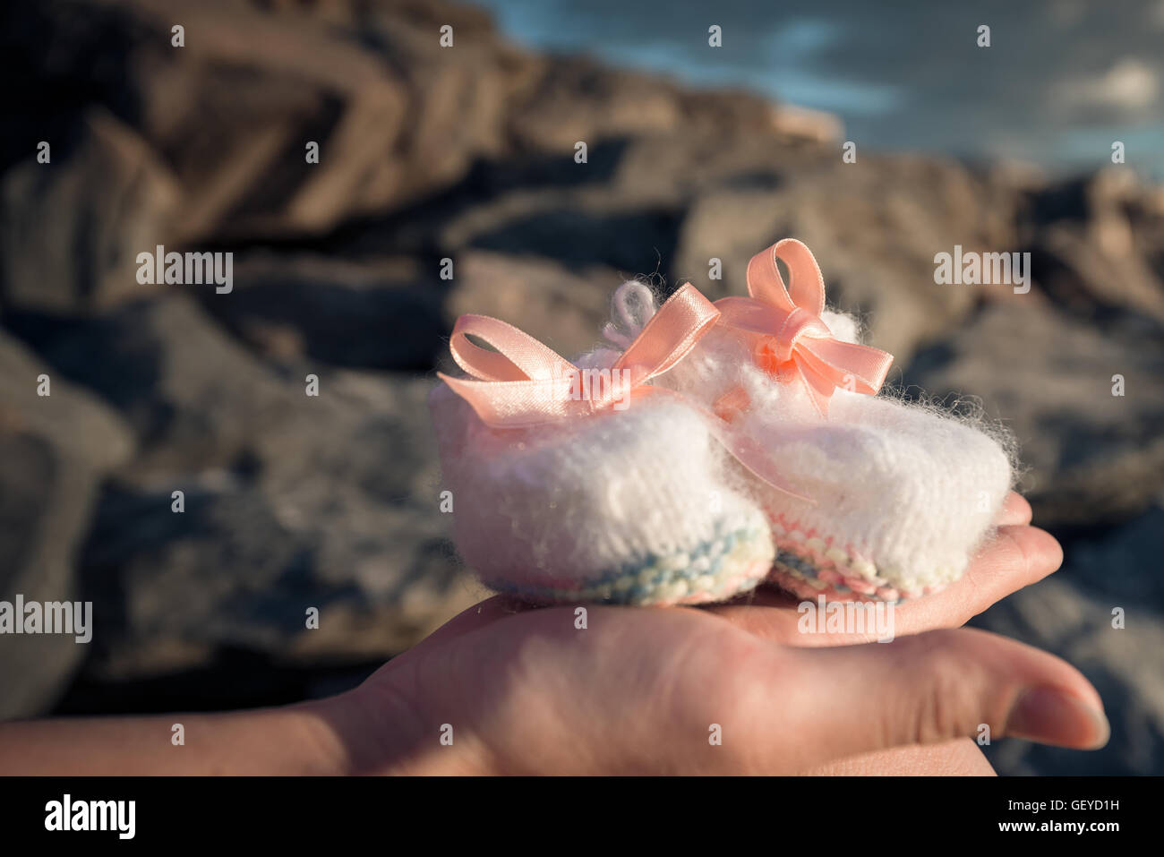 Pregnant woman holding newborn baby chaussures dans la main. La tonalité de couleur appliqué Banque D'Images