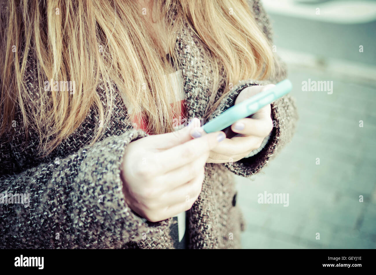 Détail de Blond Woman Holding Smart Phone dans la rue Banque D'Images