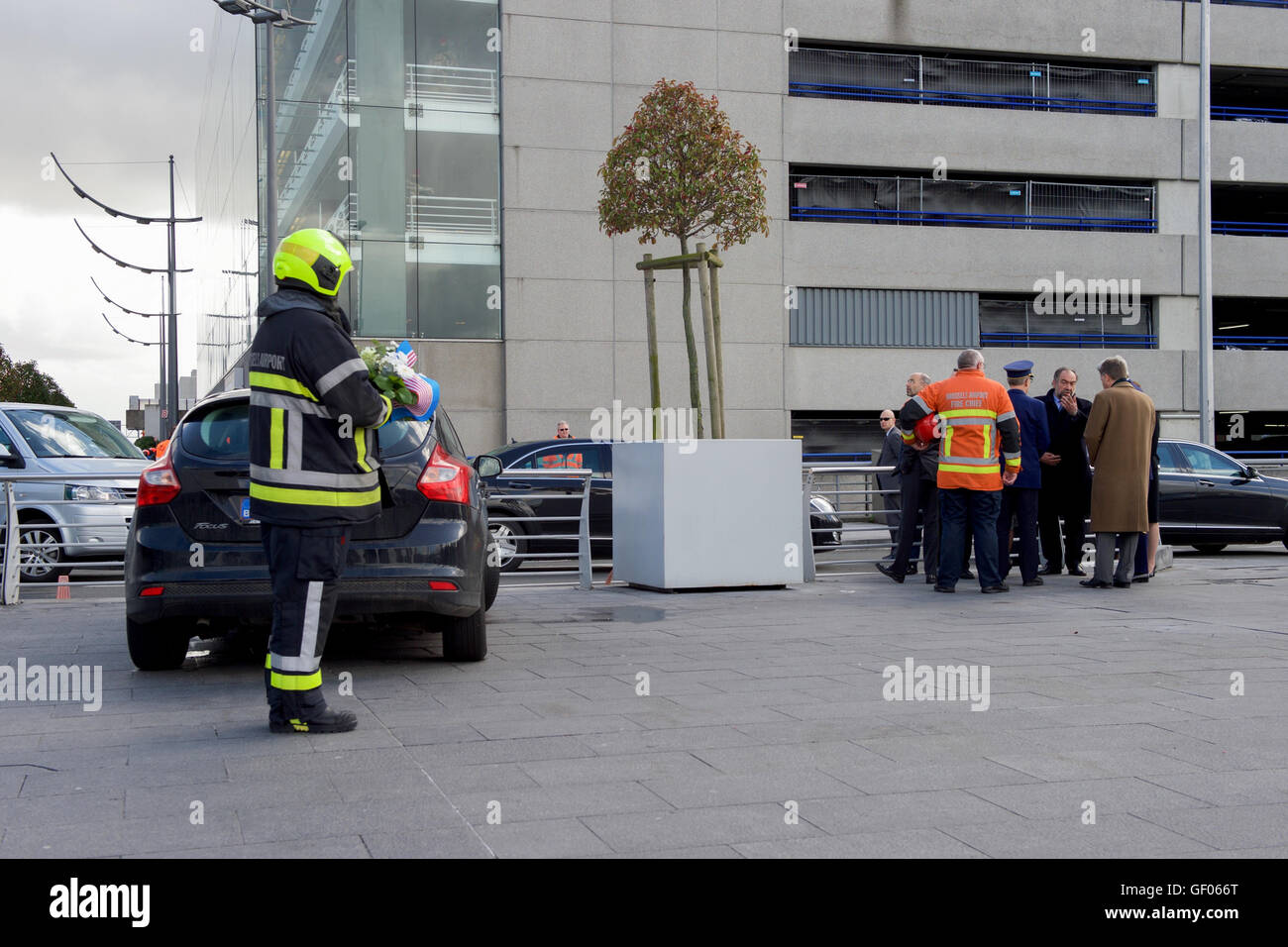 Un pompier tient une couronne alors que le secrétaire d'État John Kerry visite le terminal de l'aéroport national de Bruxelles, qui a été attaqué par des terroristes le 22 mars. Cet événement solennel marque un moment de mémoire pour les victimes et un symbole de résilience. Banque D'Images